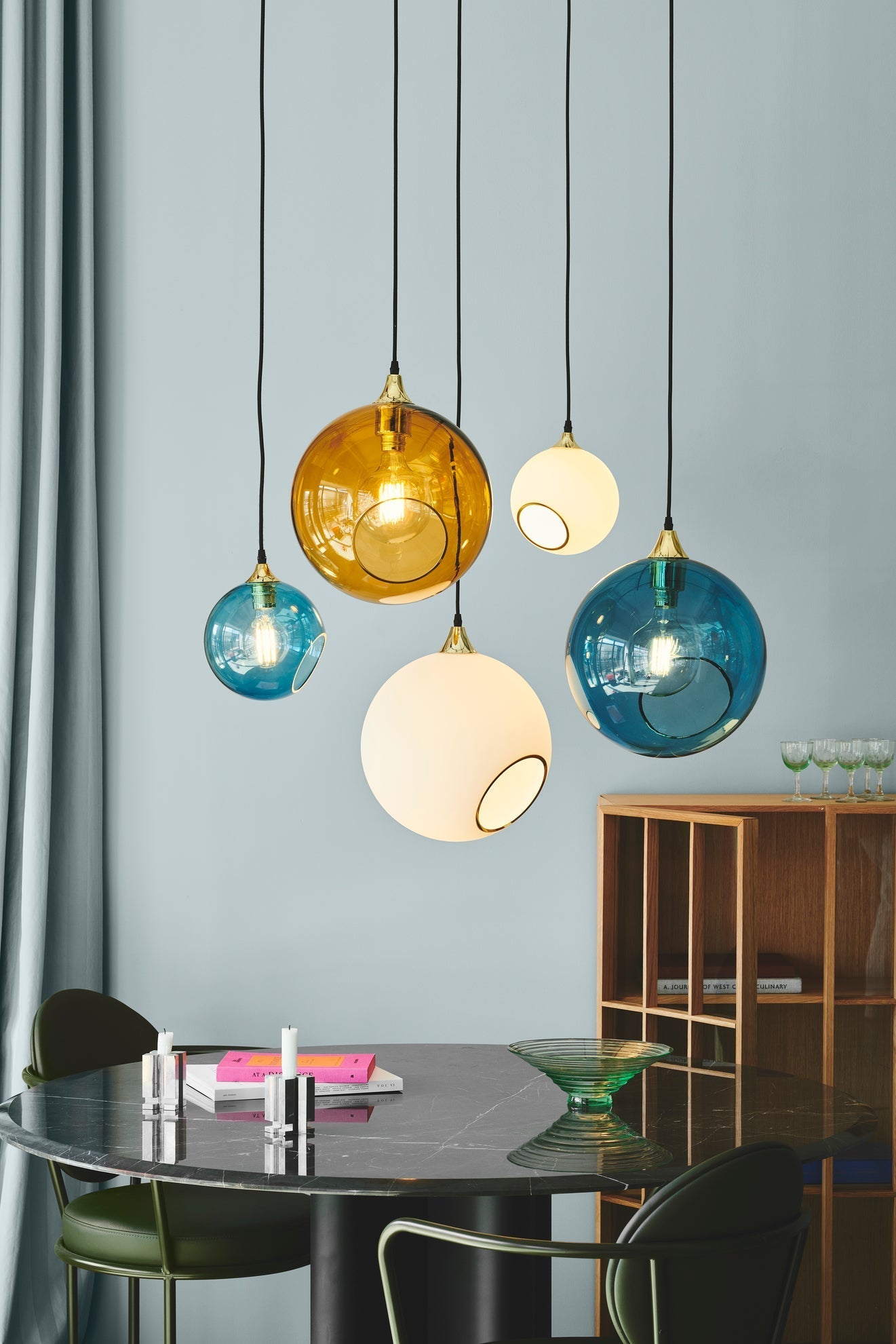 Rund lampe i hvidt glas og med et afskåret stykke med guldkant og kig til pæren. Fatning og rosetten er guldfarvet og ledningen er af sort stof.