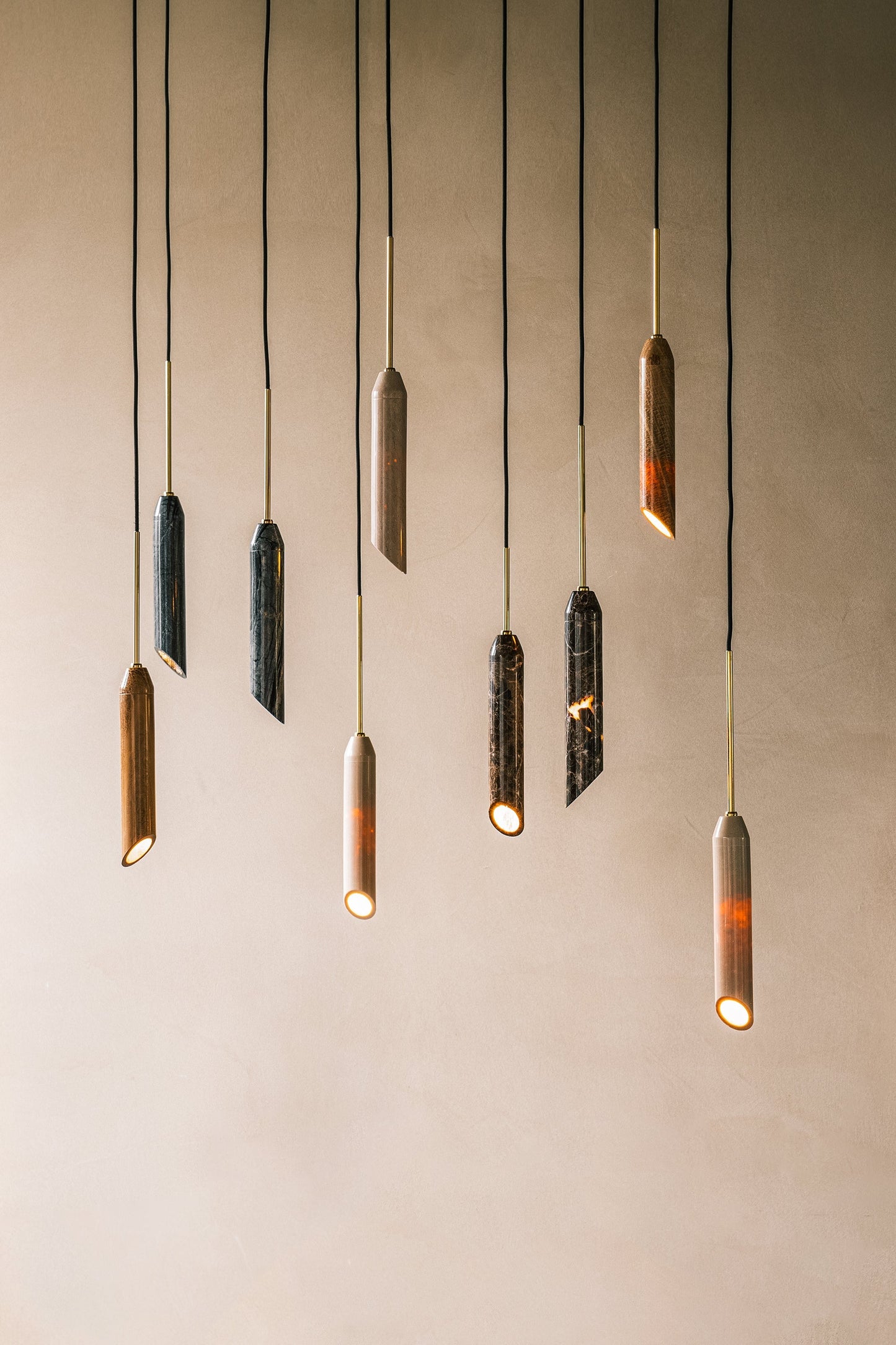 Pendel lampe i sort marmor med diagonalt snit og med guldfarvede detaljer. Lampen har en sort stofledning.