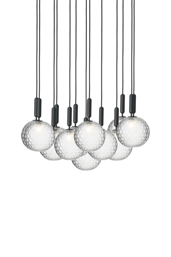 Pendel bestående af 13 runde skærme af klart optikglas med gråt ophæng og sort ledning, på hvid baggrund.