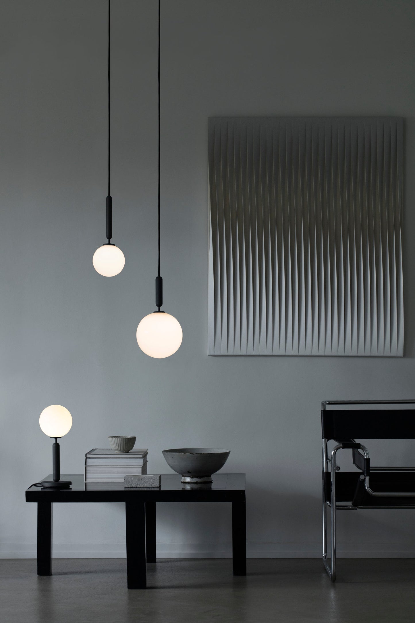 Pendel med rund skærm af opalglas og aflang grå fatning, i dagligstuemiljø