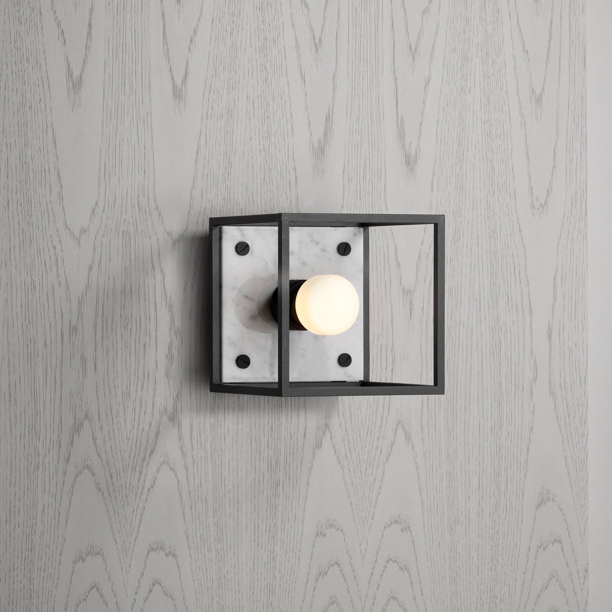 Buster and Punch caged wall lamp small i sort metal med bagplade i hvid marmor.